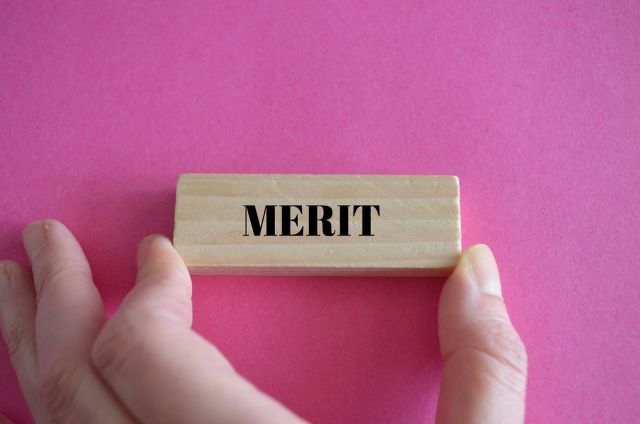 MERITと書かれたブロックを持つ女性の手